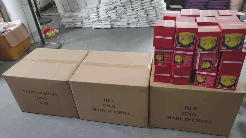 Stacked cardboard boxes labeled "Made in China" alongside red packaged mini question block lights in a warehouse ready for dropshipping