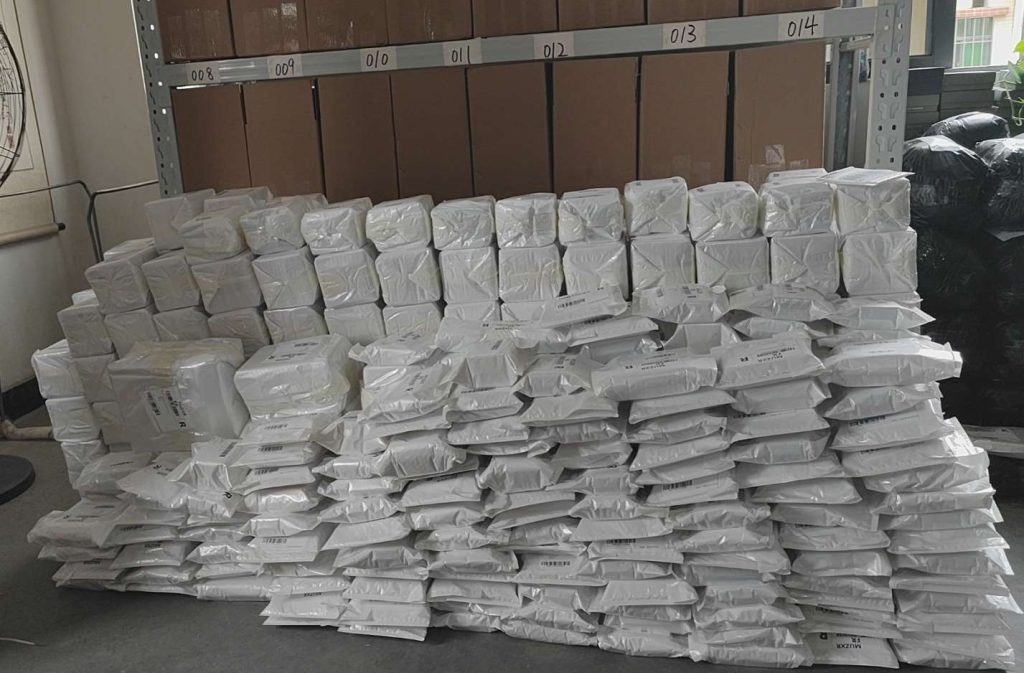 An image showing neatly packed goods from Runto, stacked and organized, ready for logistics collection. The packages are wrapped in white, with visible shipping labels, indicating that they are prepared for shipment. Shelves in the background contain additional boxes, highlighting an organized warehouse environment.