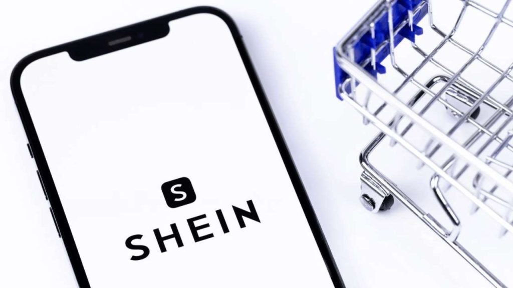 Shein logo on smartphone with mini shopping cart — a symbolic image representing the dominance of Shein in fashion eCommerce and why sellers are searching for similar sites like Shein.