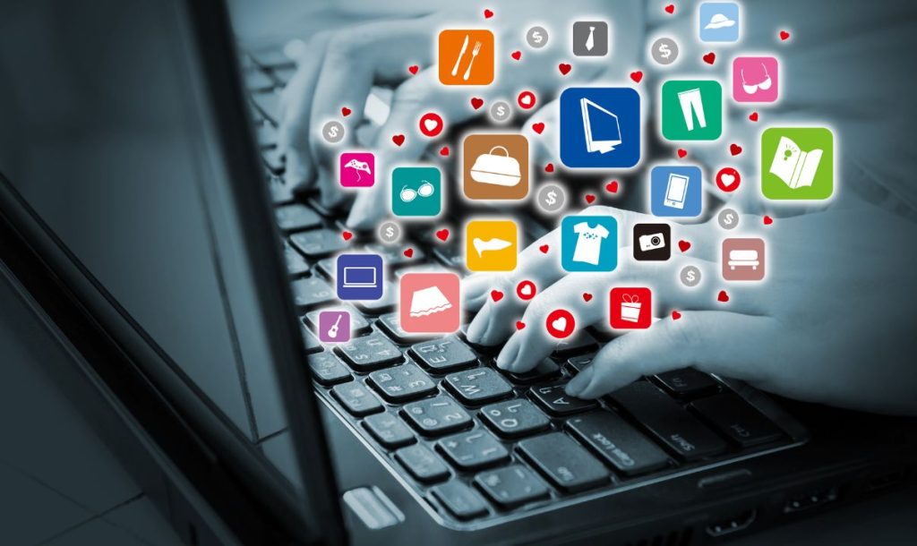 A close-up of hands typing on a laptop keyboard, surrounded by colorful icons representing various shopping categories and interests, such as clothing, gadgets, and gifts. The image is presented in a monochromatic style with vibrant icons, highlighting a digital shopping environment.